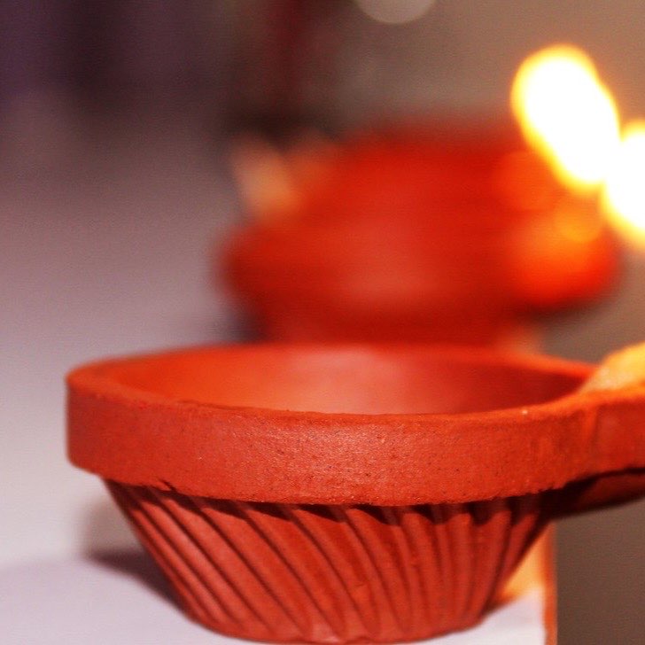 A small clay diya lamp burning with a warm flame